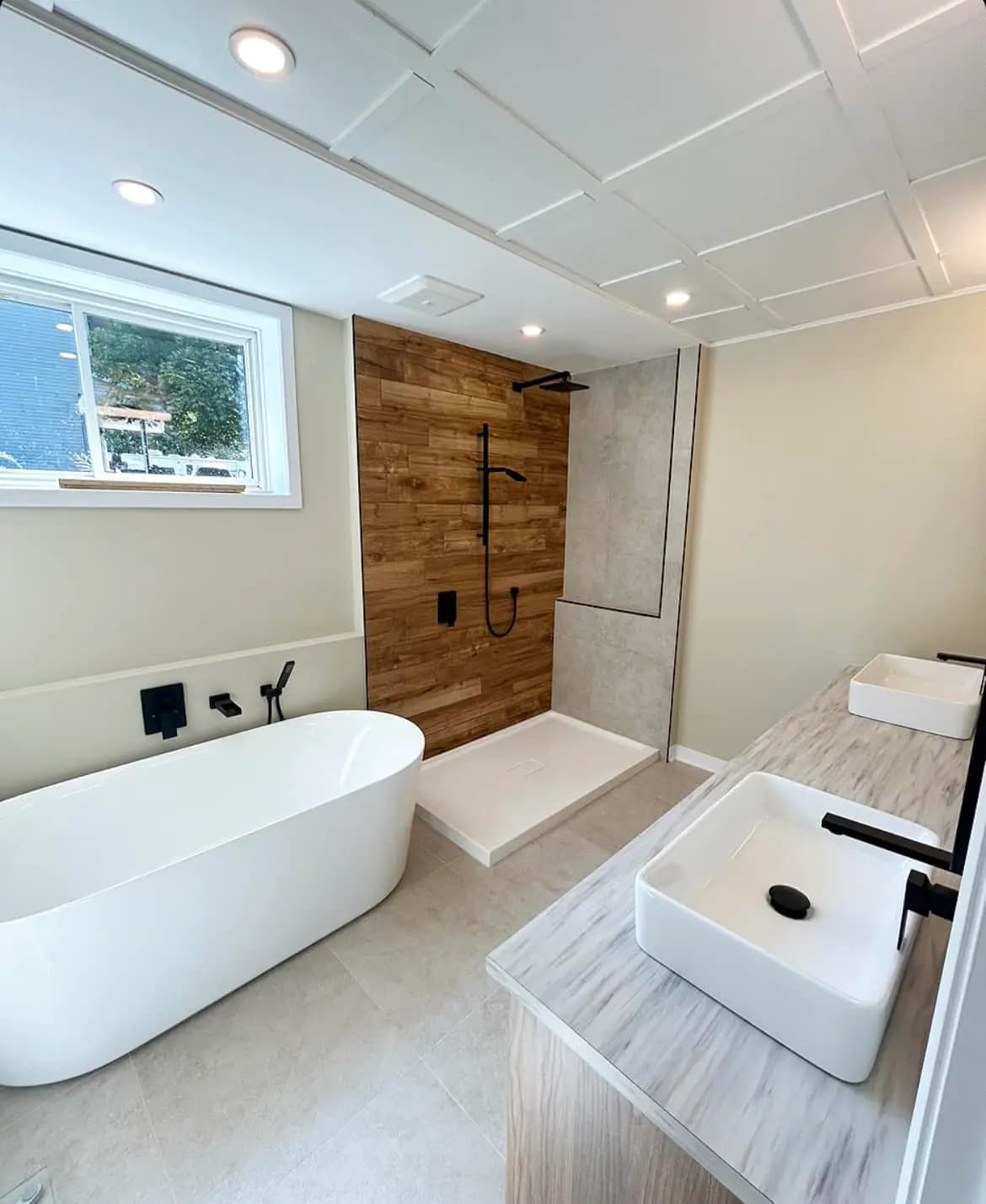 Salle de bains spacieuse avec une baignoire autoportante, une douche à l'italienne avec un revêtement en pierre naturelle et des éléments en bois pour une ambiance chaleureuse