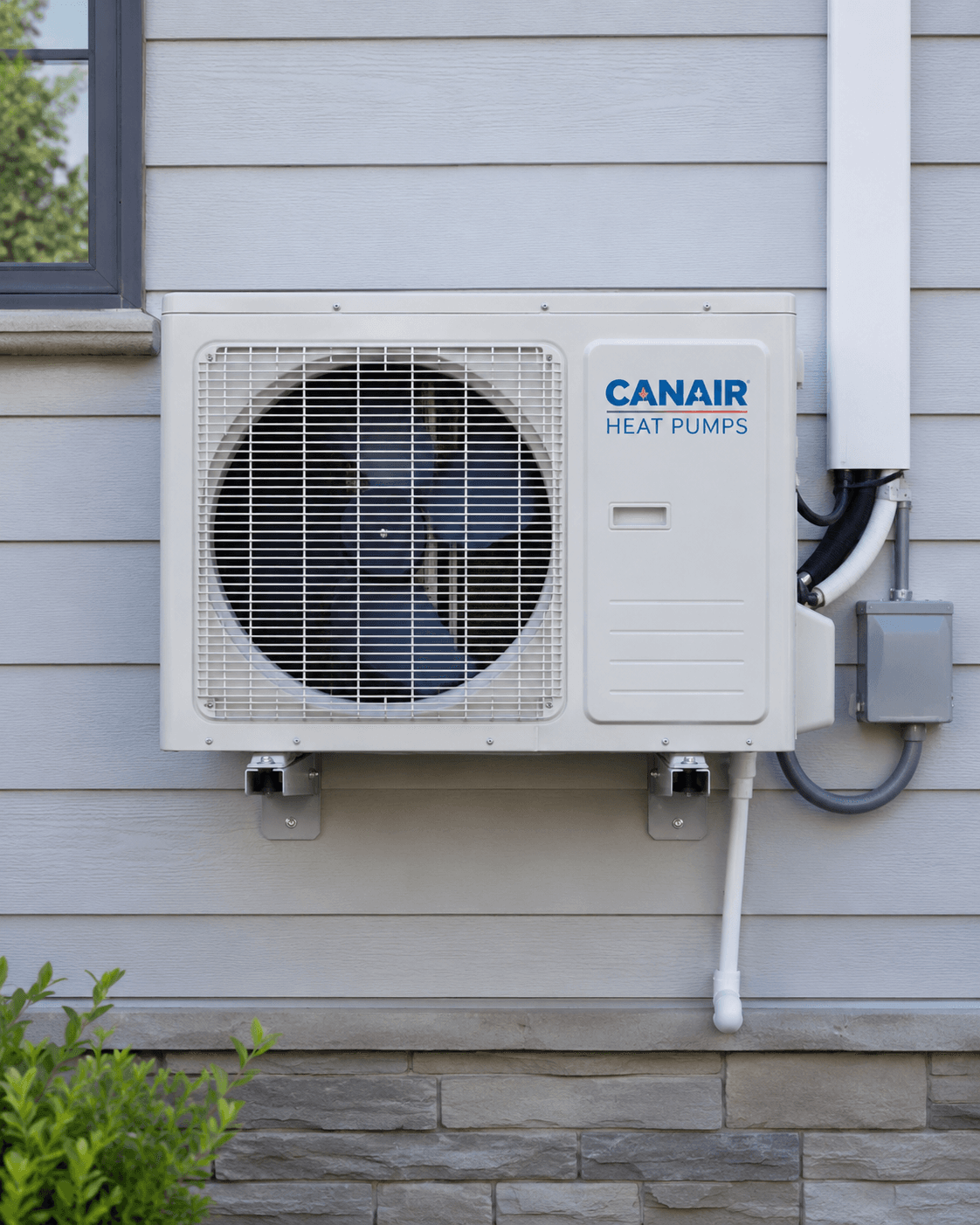 Thermopompe extérieure Canair installée sur un mur résidentiel gris, avec grille de ventilateur, conduits visibles et supports de fixation.