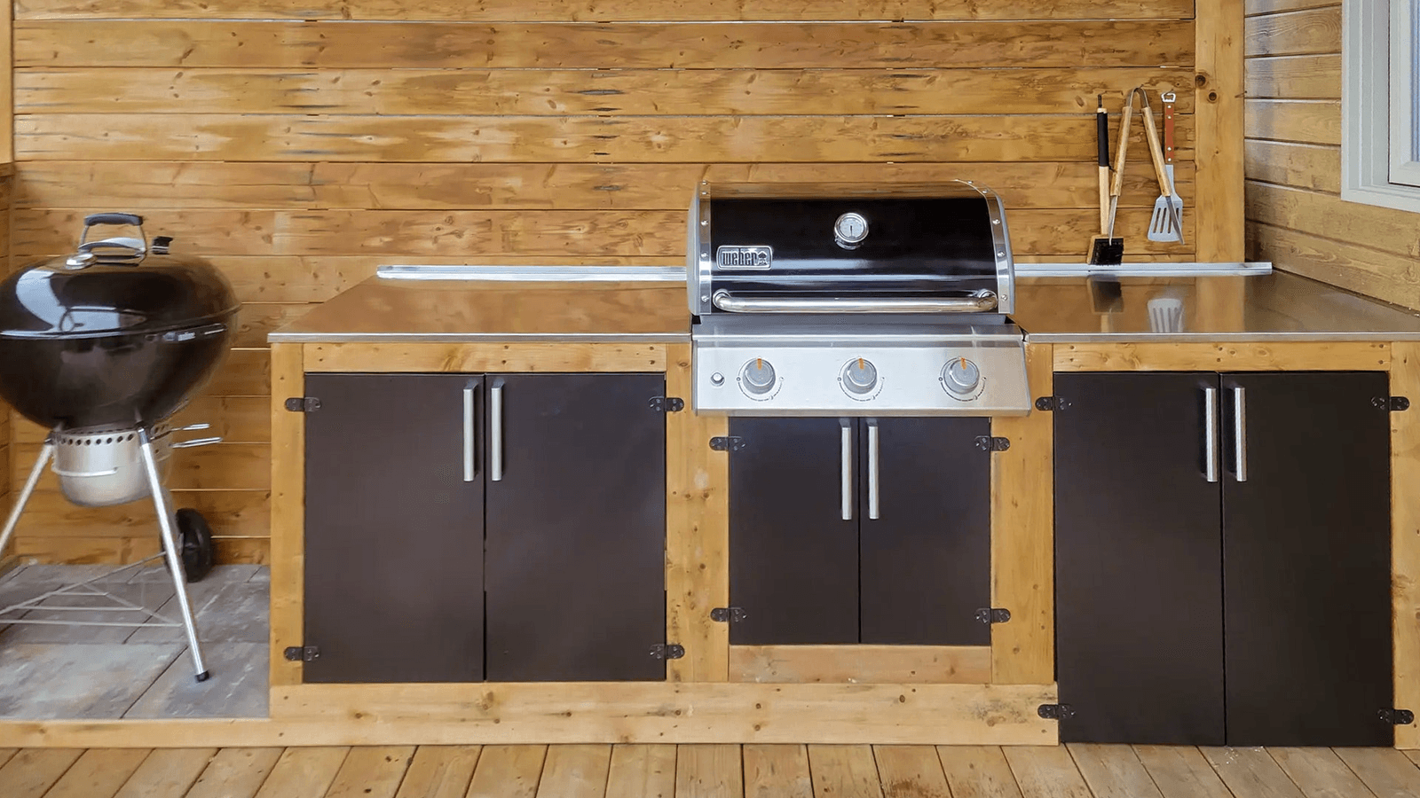 Cuisine d'extérieur en bois avec barbecue intégré et plan de travail en acier inoxydable.