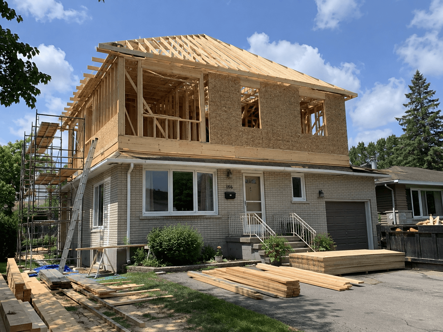 Agrandissement d’un étage résidentiel en construction avec charpente en bois, fermes de toit, panneaux structuraux, échafaudage et matériaux de chantier