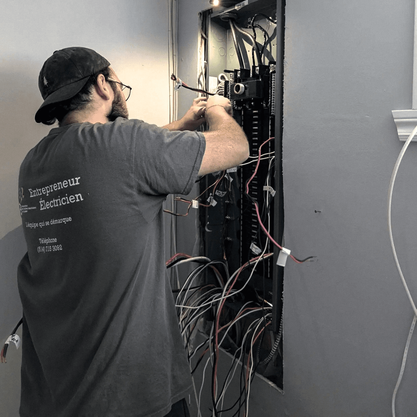Électricien effectuant le raccordement et l’organisation du câblage dans un panneau électrique résidentiel encastré.