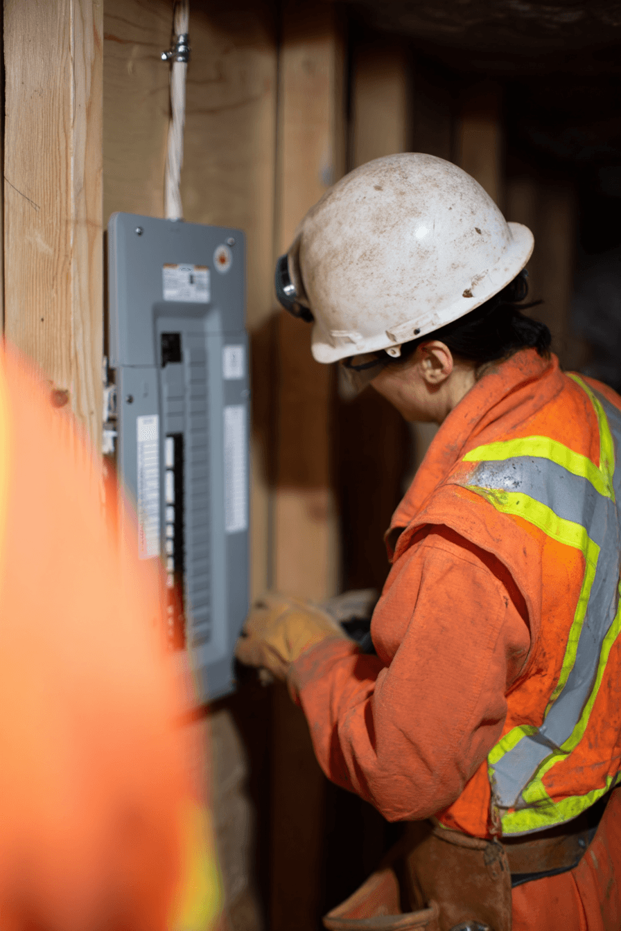 Électricien avec casque de sécurité travaillant sur un panneau électrique dans une structure en bois en construction