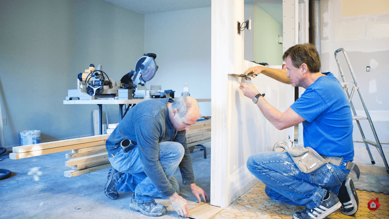 Deux ouvriers travaillant à l'installation de cloisons sèches et de revêtements de sol dans une maison résidentielle en pleine rénovation