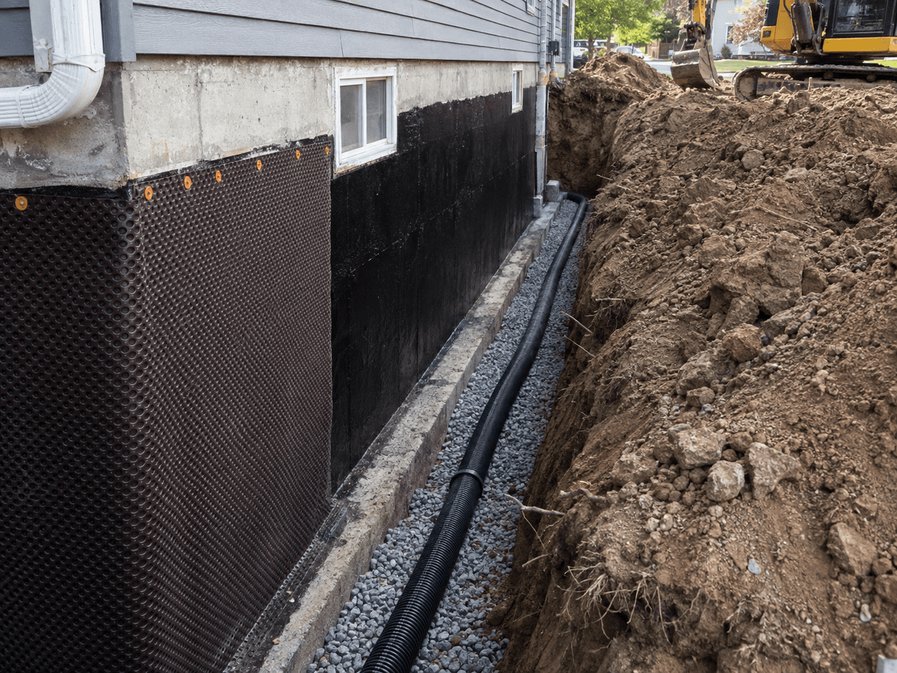 Installation d’un drain français extérieur le long des fondations d’une maison avec membrane drainante, tuyau perforé, gravier et excavation