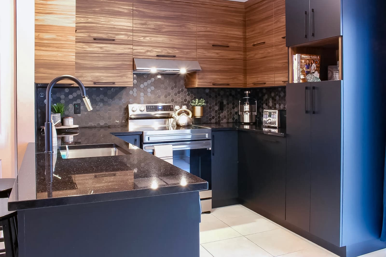 Cuisine moderne avec armoires en bois et noires, dosseret en tuiles hexagonales et comptoir en quartz noir.