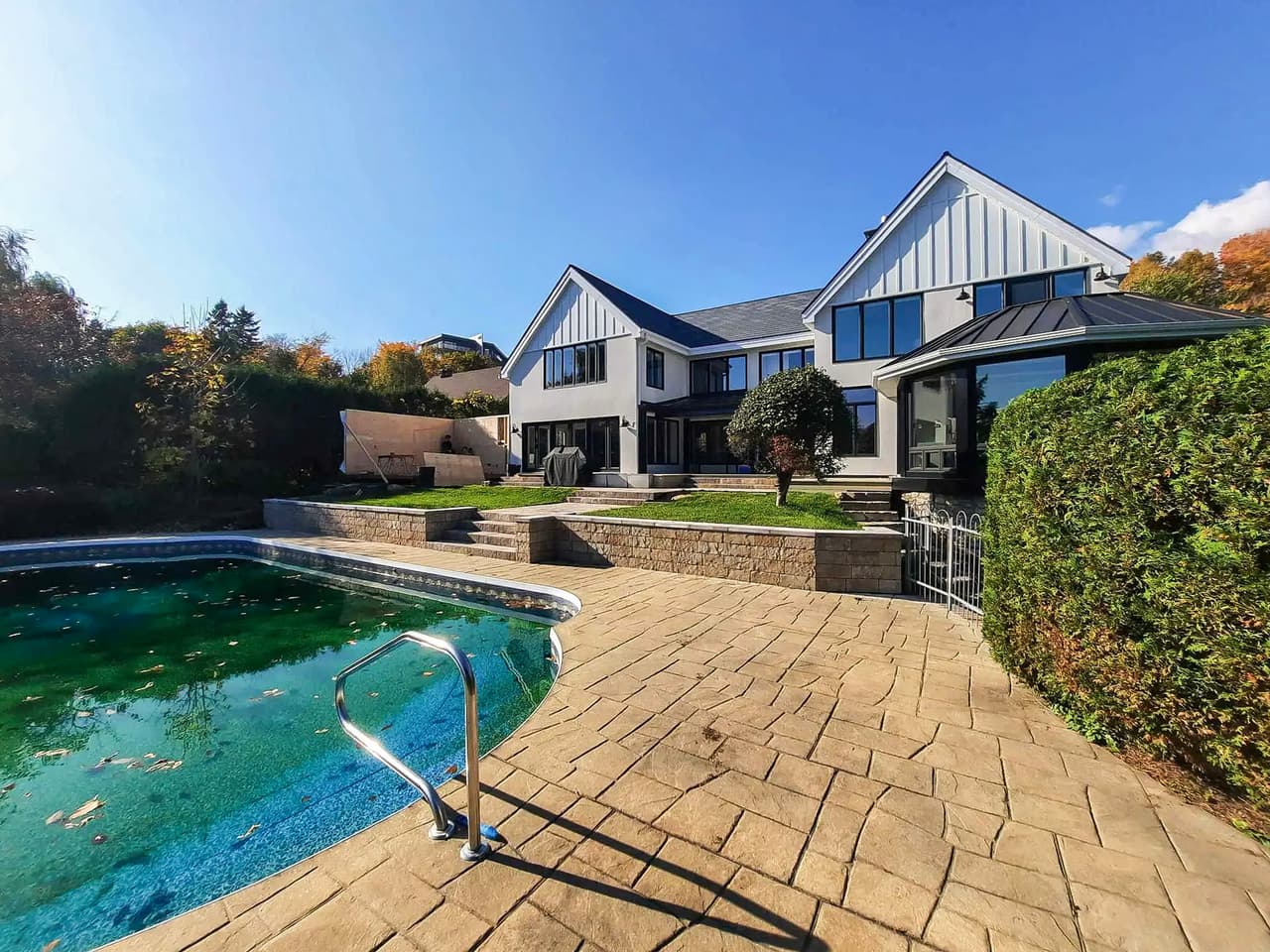 Cour arrière résidentielle avec piscine creusée, terrasse en béton estampé et aménagement paysager