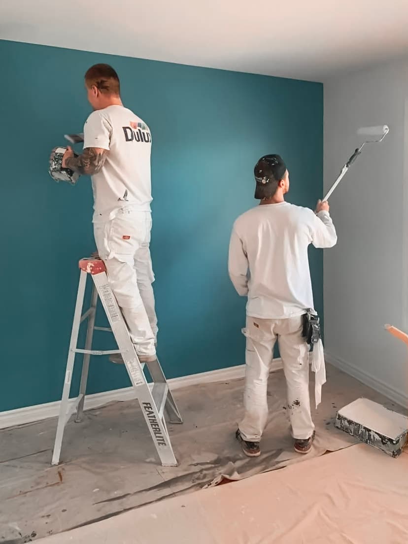 Travaux de peinture intérieure réalisés par des peintres professionnels appliquant de la peinture bleue sur un mur dans le cadre d’une rénovation moderne.