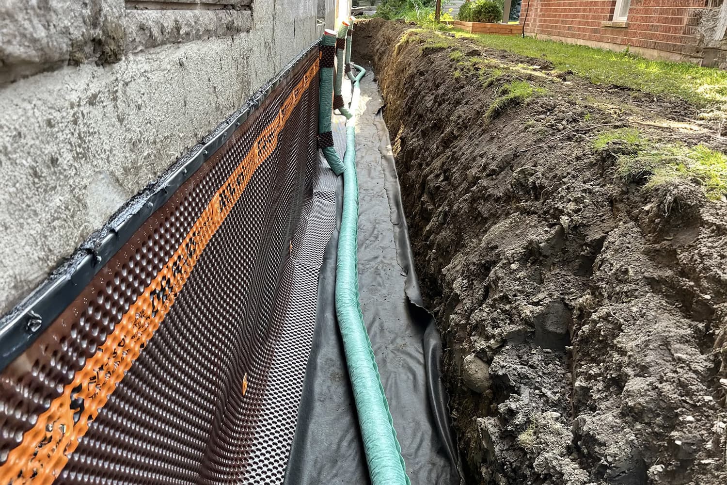  Installation d’un drain français avec membrane d’étanchéité le long des fondations d’une maison.