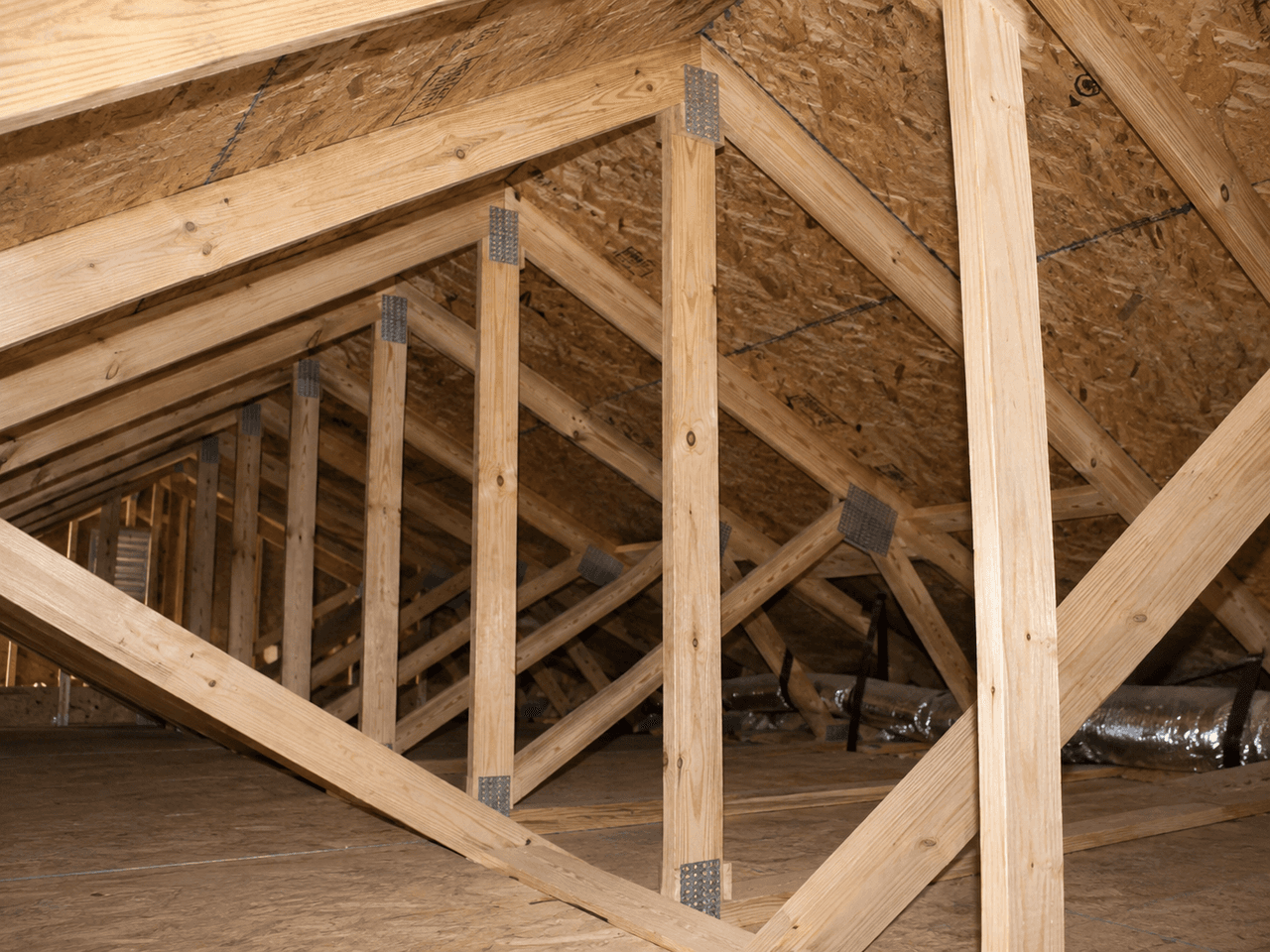Charpente de toiture en bois dans un grenier résidentiel avec fermes, montants, contreventements et panneaux structuraux en bois