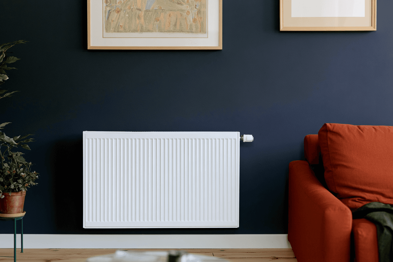 Radiateur mural blanc installé dans un salon moderne avec mur bleu foncé, canapé orange et décoration intérieure contemporaine