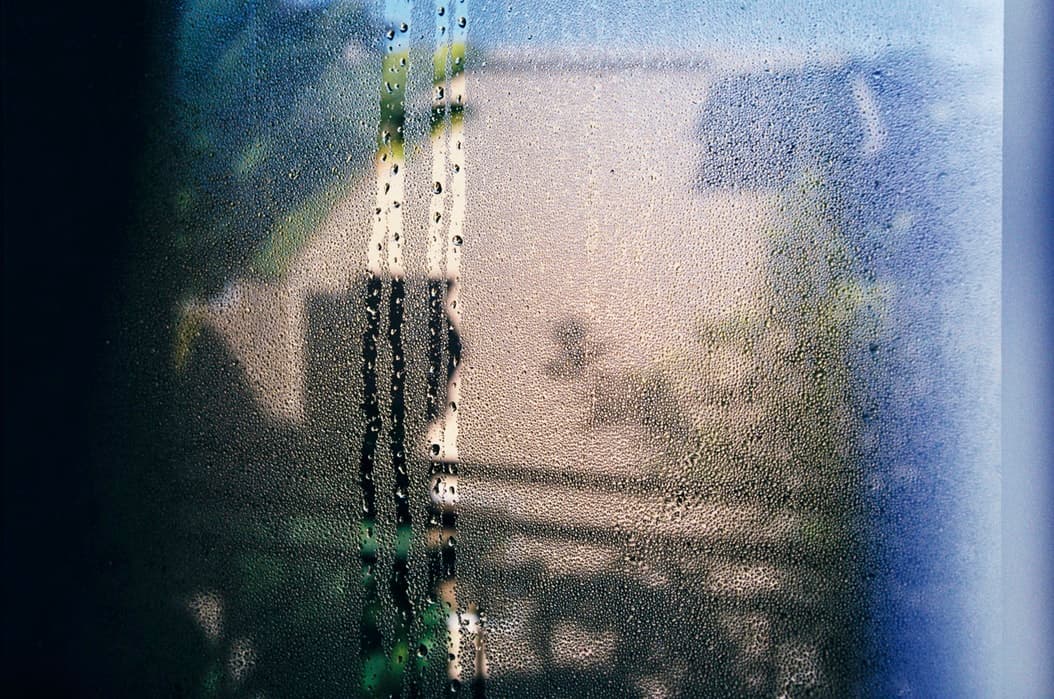 Gros plan de fenêtres couvertes de buée dense et de gouttes de condensation d'eau ruisselant le long de la vitre
