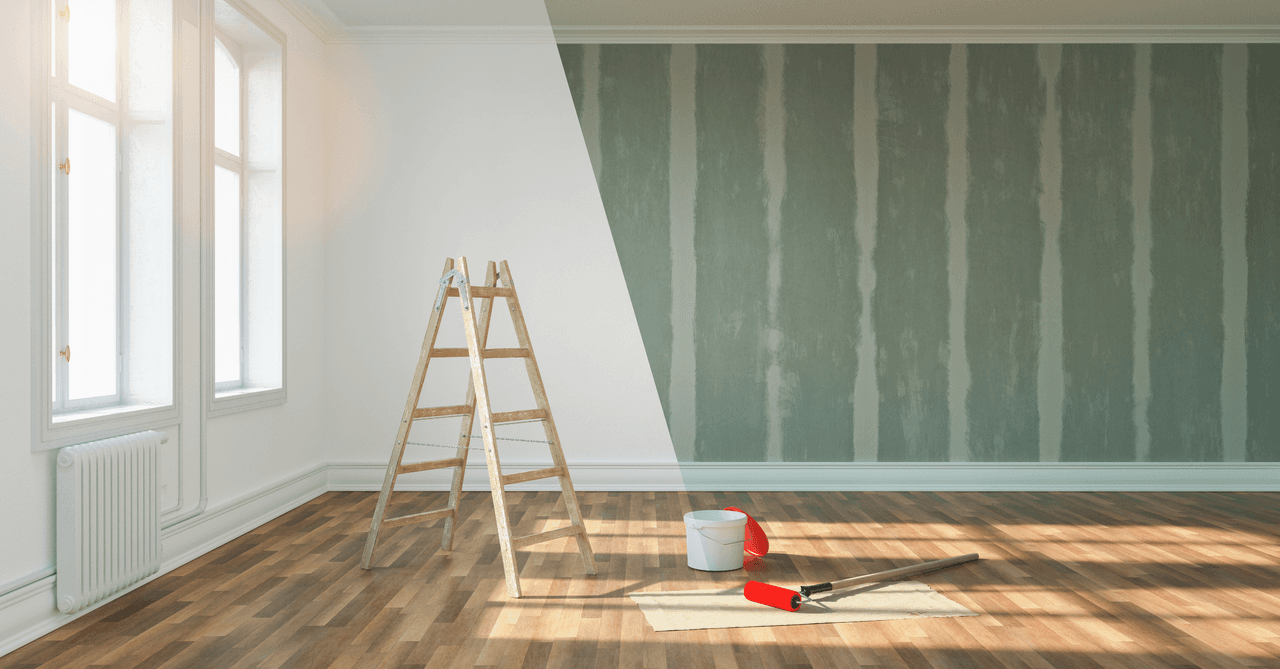 Rénovation d'une pièce : moitié du mur repeinte en vert clair, peinture blanche sur l'autre moitié, échelle en bois, pot de peinture et rouleaux, sol en parquet.