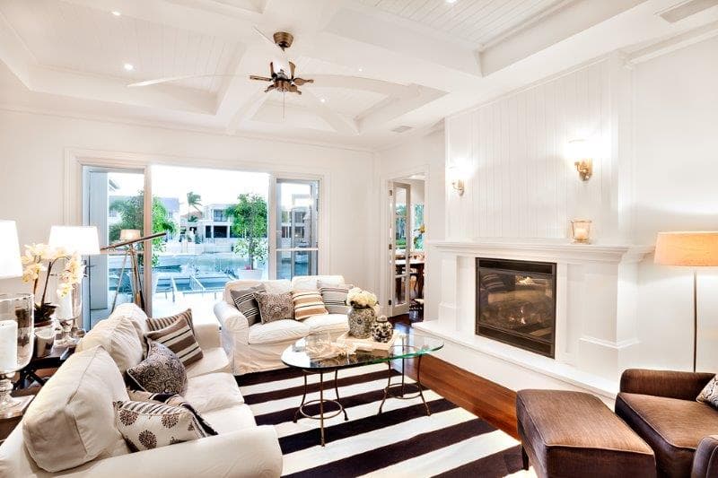 Grand salon lumineux au style moderne et élégant avec un foyer encastré au gaz, un manteau blanc et un plancher en bois.