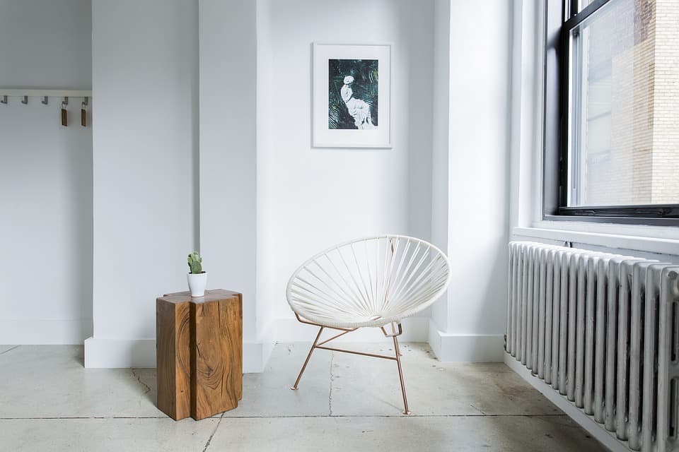 Coin de pièce moderne et épuré avec sol en béton poli, chaise ronde contemporaine et radiateur classique.